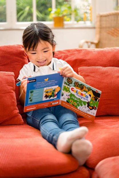 Enfant feuilletant le livre Coloréo magique, pages ouvertes avec animaux