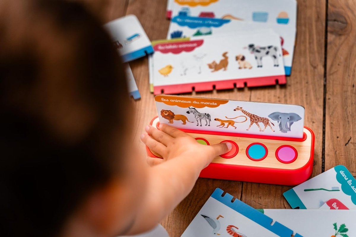 Mains utilisant Mon Imagier Parlant : carte illustrée posée sur le boîtier à boutons