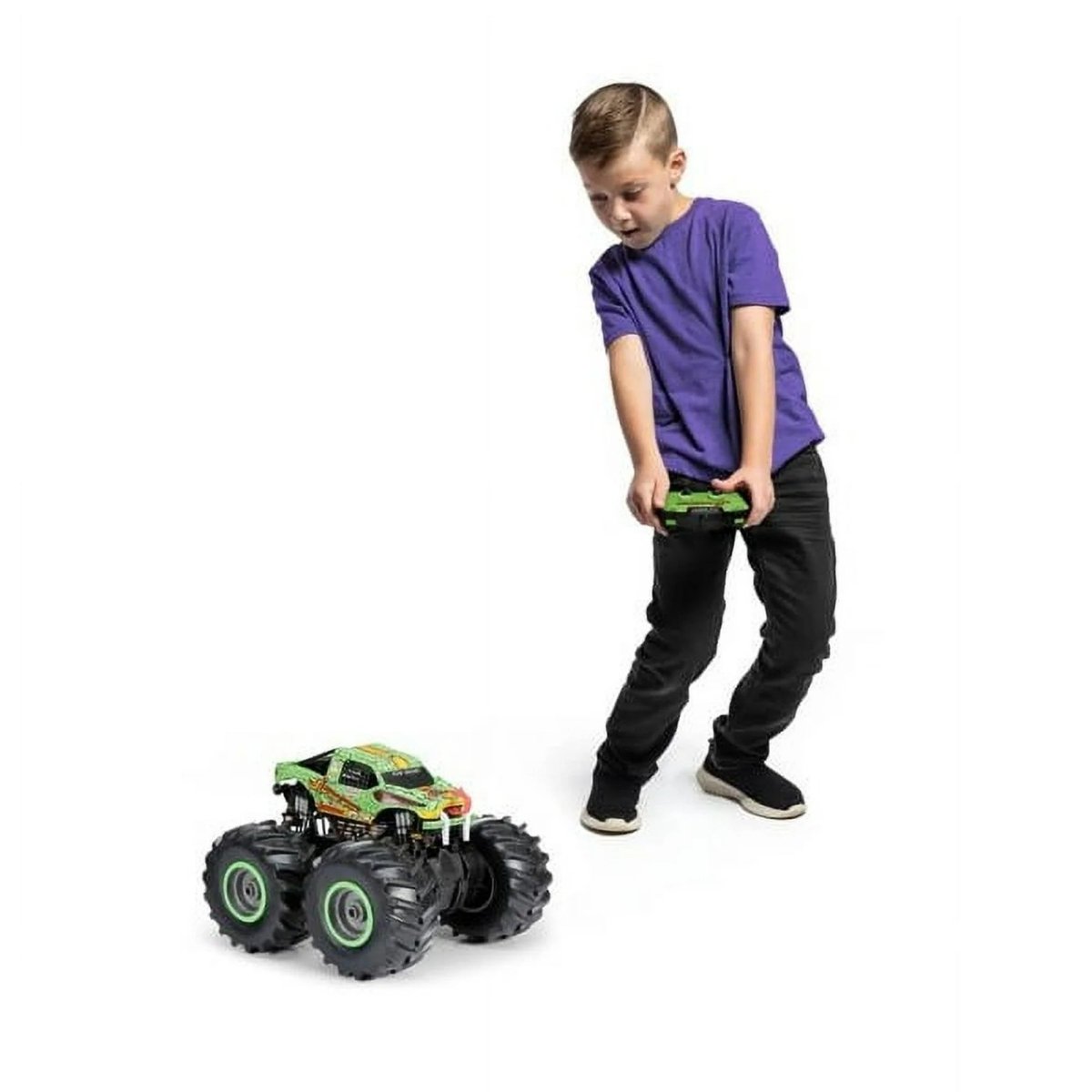 RC monster truck toy with green top and black tires; child holds controller in front view.