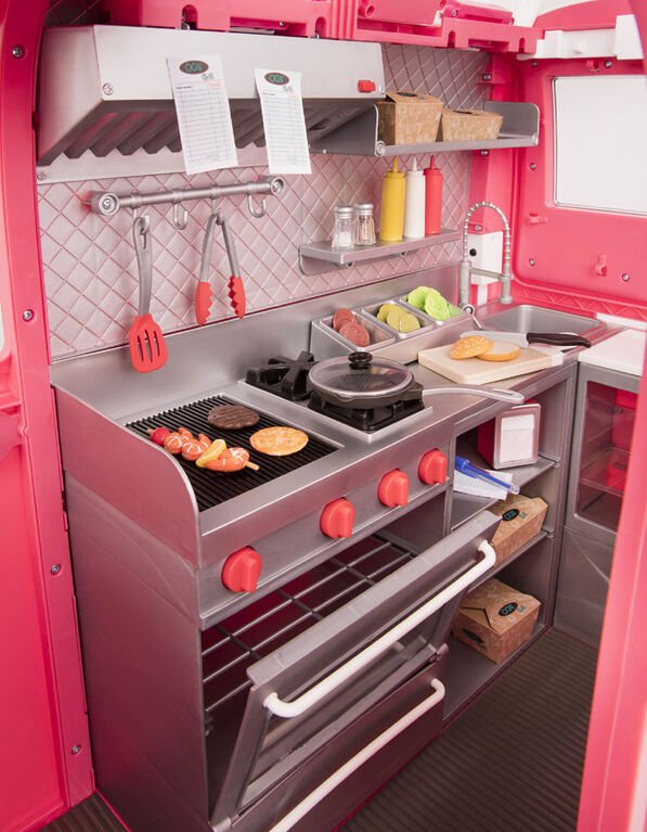 Pink toy food truck playset interior with grill, pans, utensils, and ingredient trays