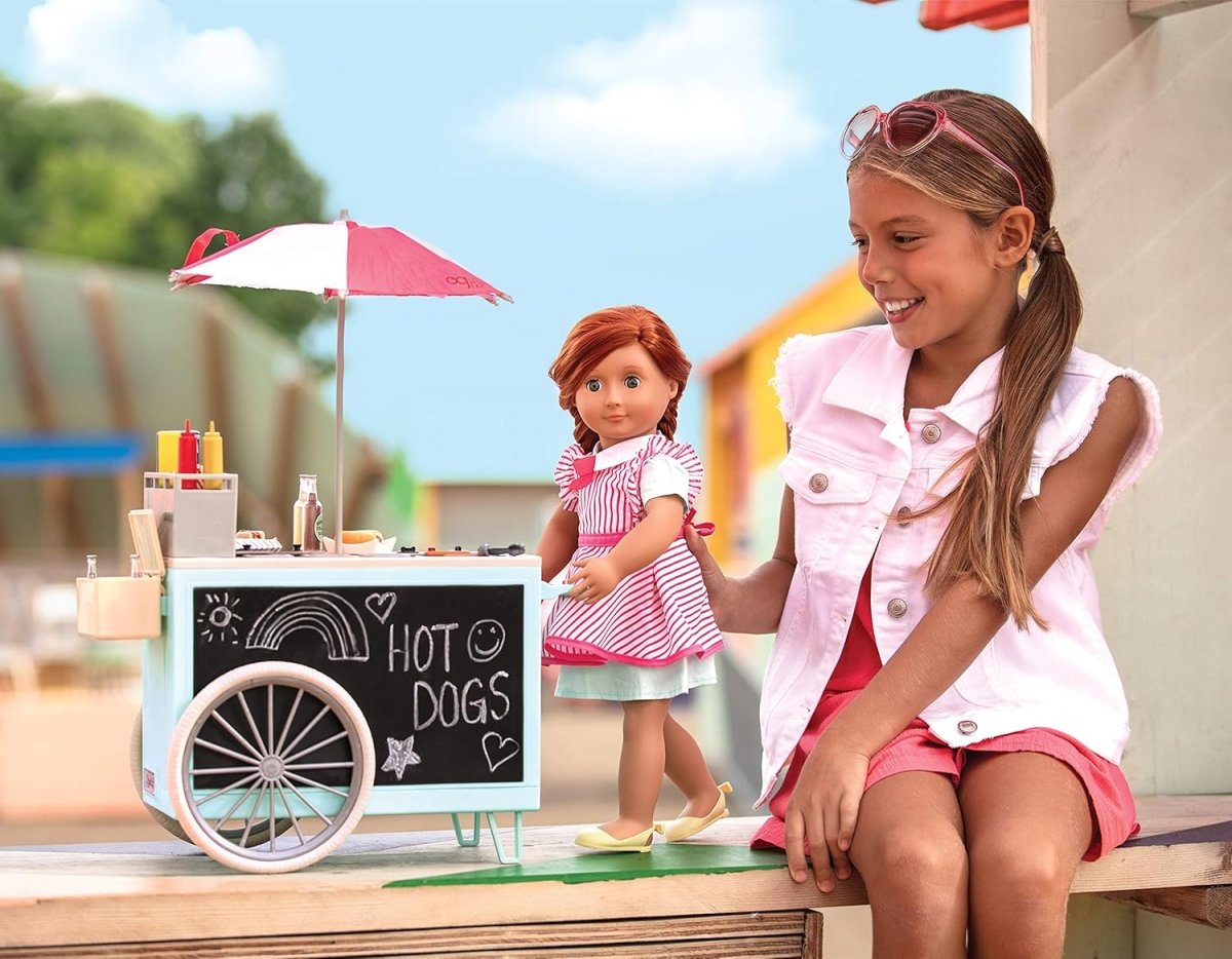 Toy hot dog cart with umbrella beside a girl holding a doll