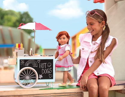 Toy hot dog cart with umbrella beside a girl holding a doll