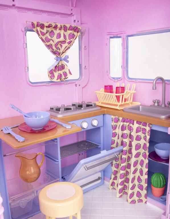 Camper trailer interior kitchen with sink, stove, faucet, and purple pattern curtains