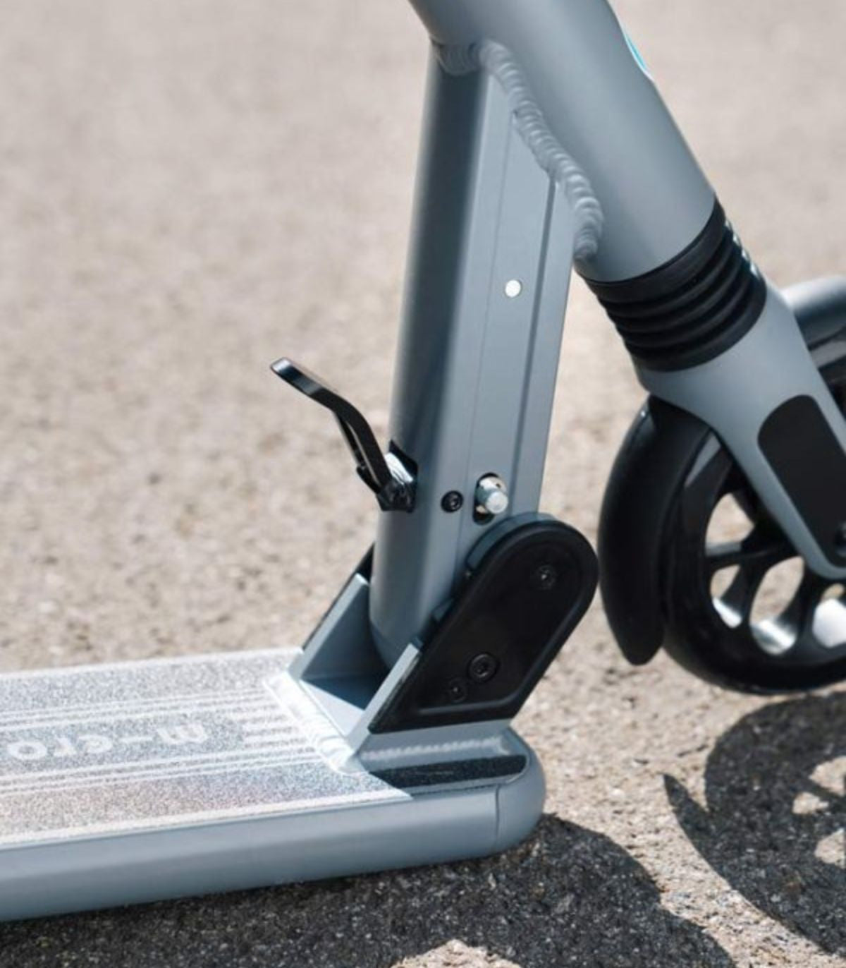 Dark gray scooter deck and fork with shock suspension, close-up on wheels