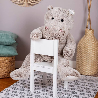Giant gray plush hippo sitting on a white chair, stitched smile and pink blush cheeks