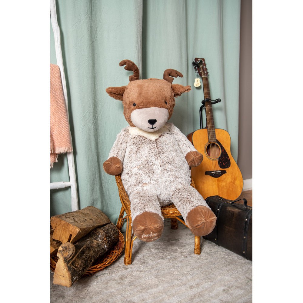 Plush reindeer toy seated on a chair, brown head with white muzzle and light gray fur.