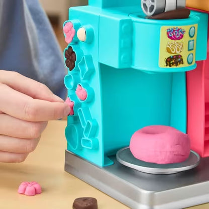 Play-Doh donut drop machine with pink and brown dough pieces near the plate