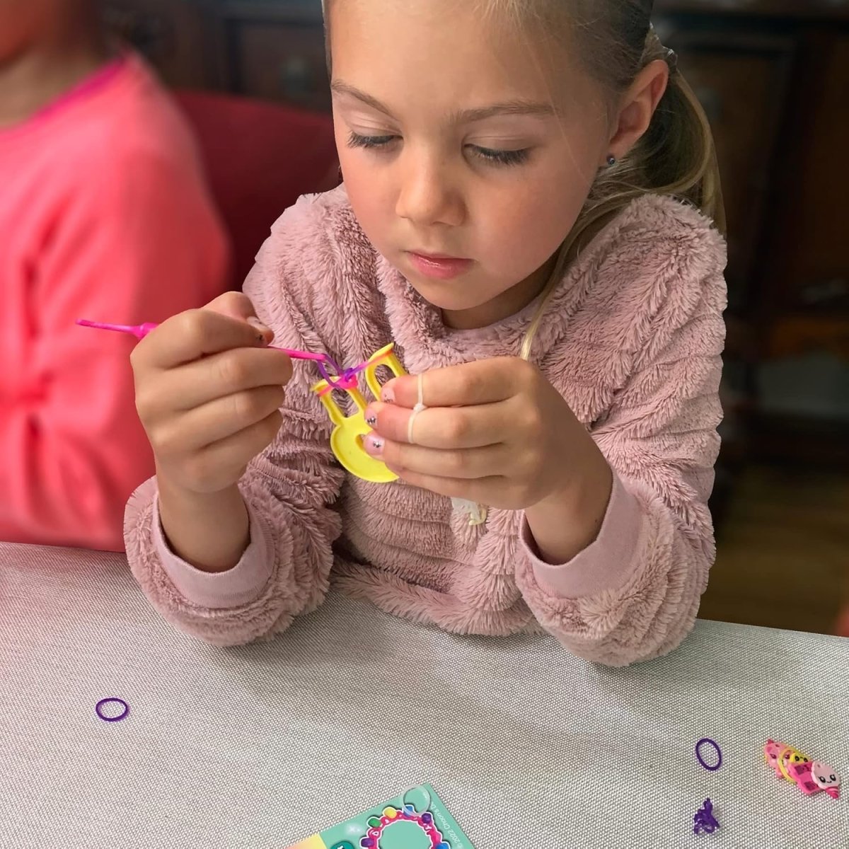 Kind bastelt mit Rainbow Loom Schablone und bunten Gummibändern
