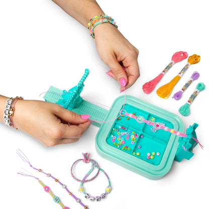 Hands using Wrapit Loom teal base to weave friendship bracelets with multicolor threads