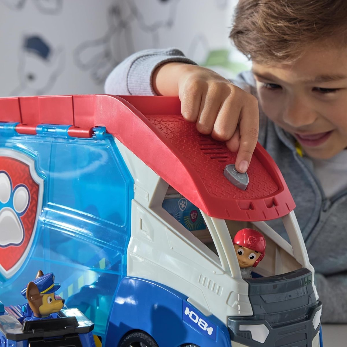 Child hand placing a Paw Patrol figure into the open patroller pack launcher