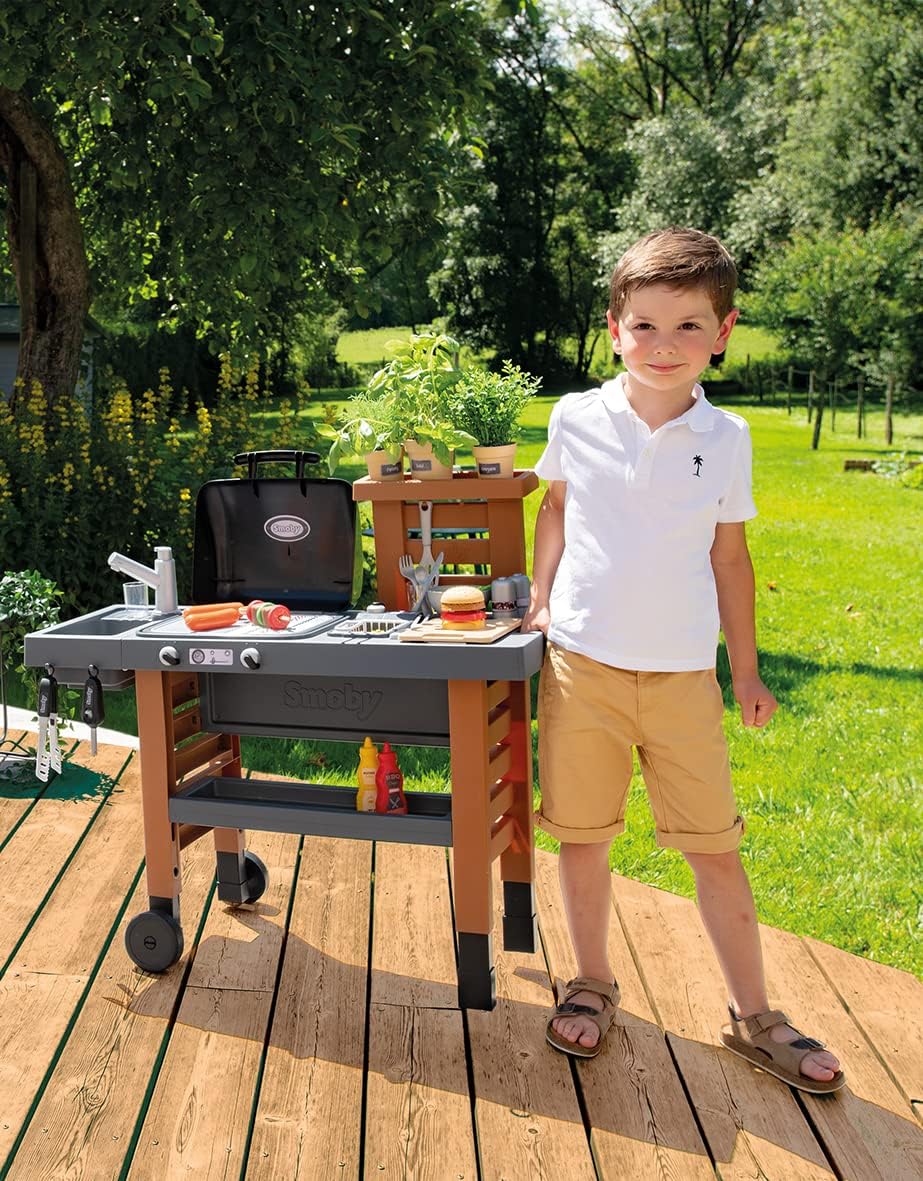 Outdoor garden kitchen play grill with gray counter, black hood, and side tool hooks