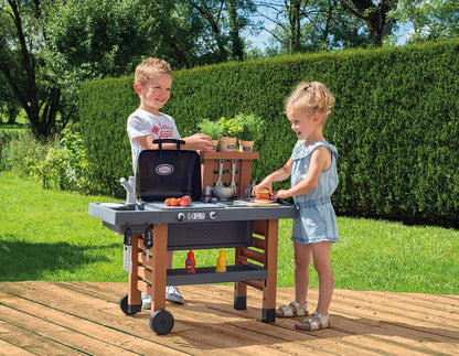 Kids garden kitchen play grill with shelves and cooking accessories, on outdoor patio