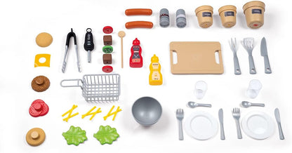 Assorted play food and kitchen accessories: pans, plates, cutlery, and seasoning bottles