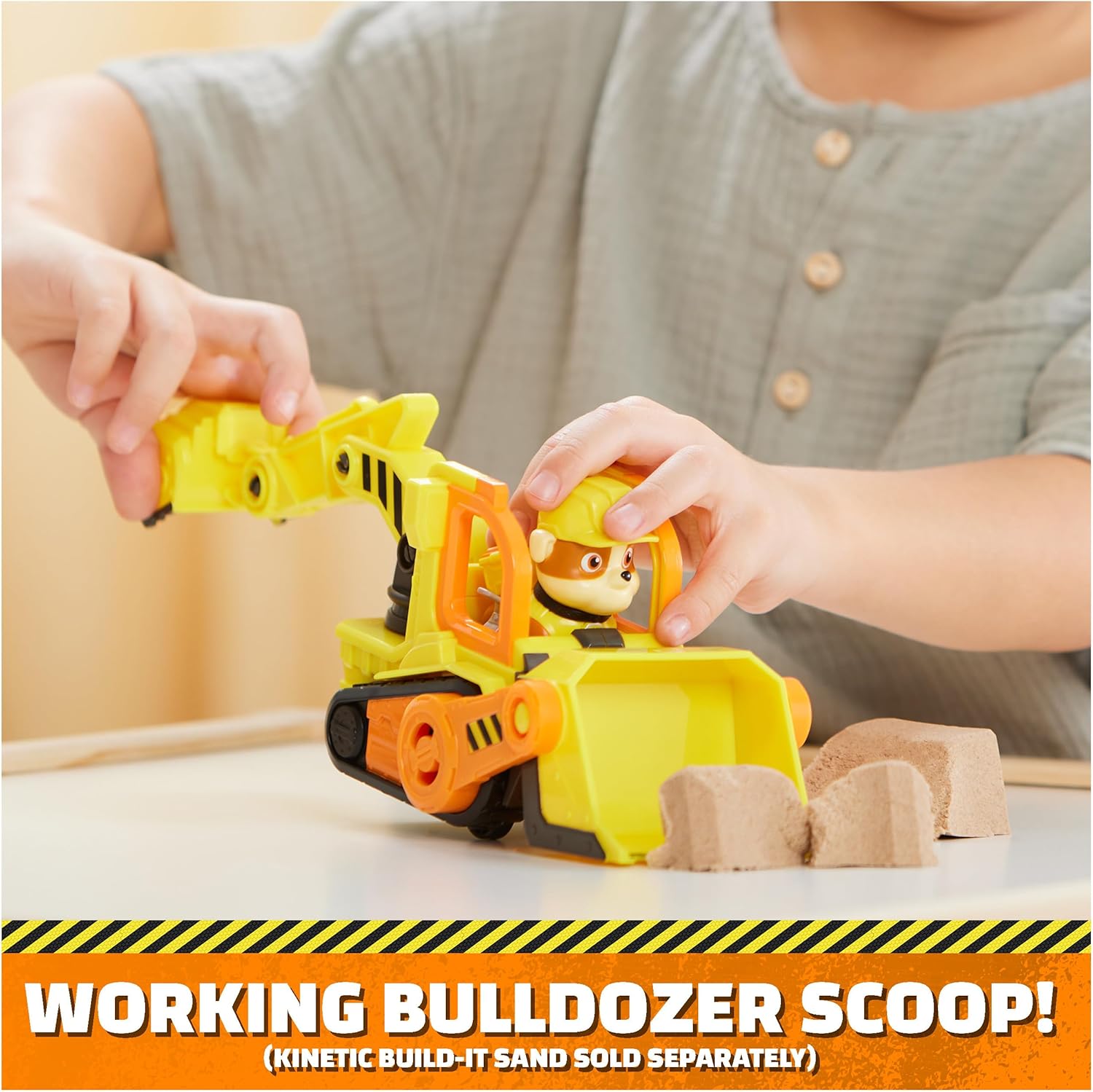 Child hands placing Rubble figure into yellow bulldozer toy with front scoop