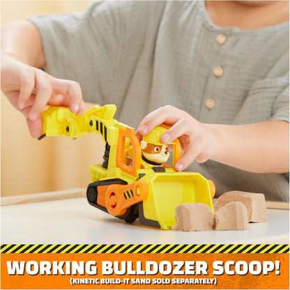 Child hands placing Rubble figure into yellow bulldozer toy with front scoop
