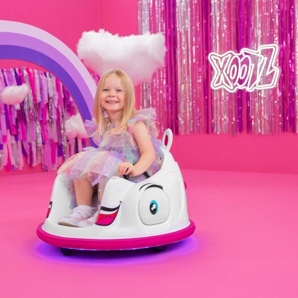 Girl seated in white unicorn bumper car ride-on with rainbow horn and magenta base