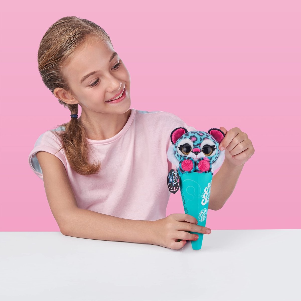 Plush animal surprise toy in turquoise cup, held by a child